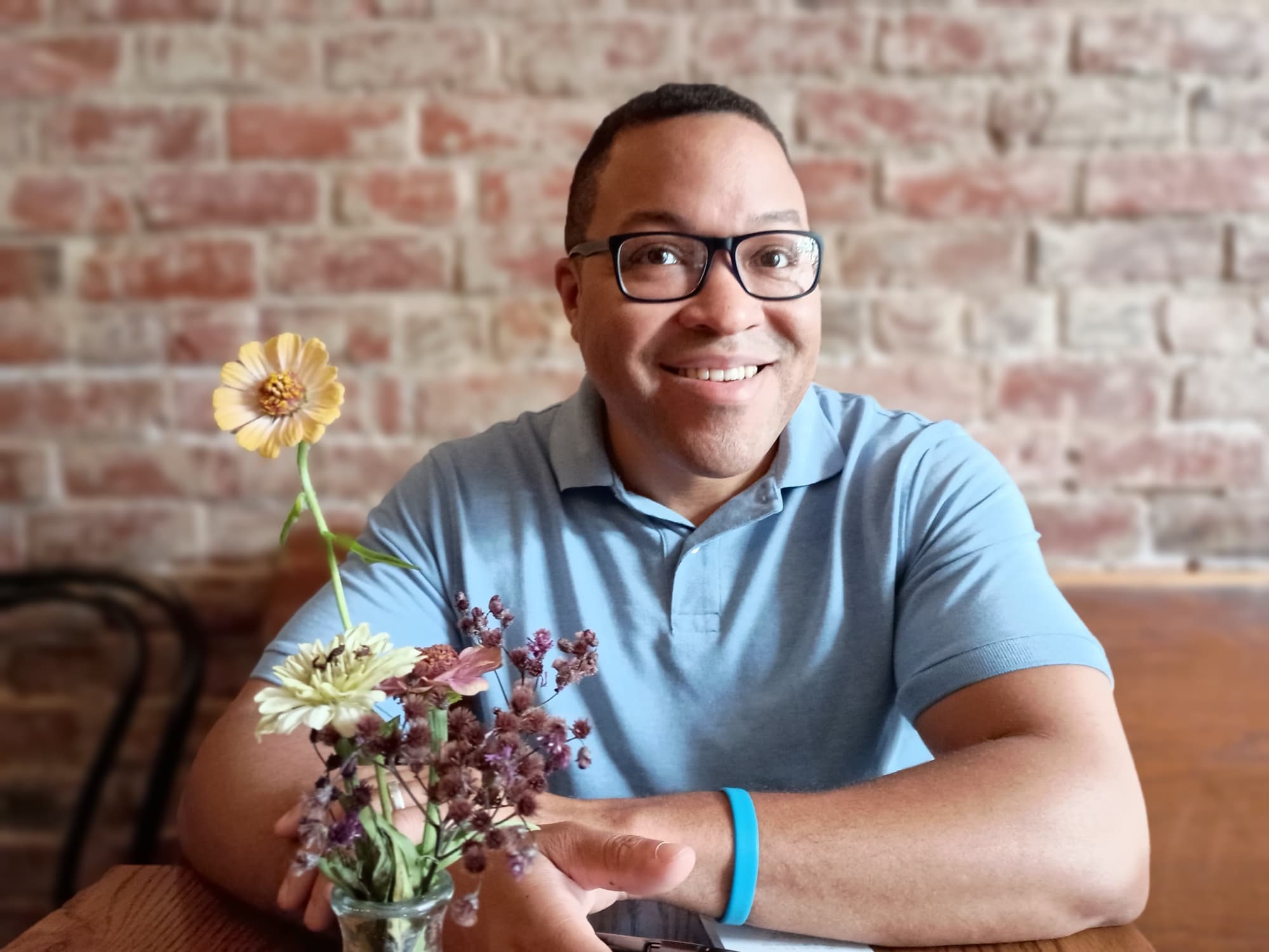 Nathan Jeffers with a brick wall in background, wearing a light blue polo shirt and looking at the camera with a slight smile.
